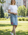 The Strawberry Shop light wash denim skirt with pink floral embroidery at the hem and waistband. Knee length.