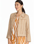 Model wearing The Strawberry Shop FOIL sand linen jacket with fringe trim over a patterned dress