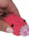 The Strawberry Shop handmade pink crochet blob keychain with bead eyes and a clear sphere filled with pink beads.