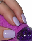 The Strawberry Shop purple crochet blob keychain with a textured chenille finish held in a hand with lilac nails.