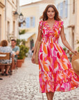 The Strawberry Shop Foil Dress FO8202, a vibrant pink, orange, and white abstract print midi dress with ruffled neckline and tiered skirt.