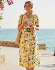 The Strawberry Shop white 100% cotton midi dress with short sleeves, V-neck, button front, and a vibrant lemon print. Features a belted waist with a wooden buckle.