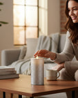 The Strawberry Shop black brick water candle with LED light on a wooden table next to a smiling woman.
