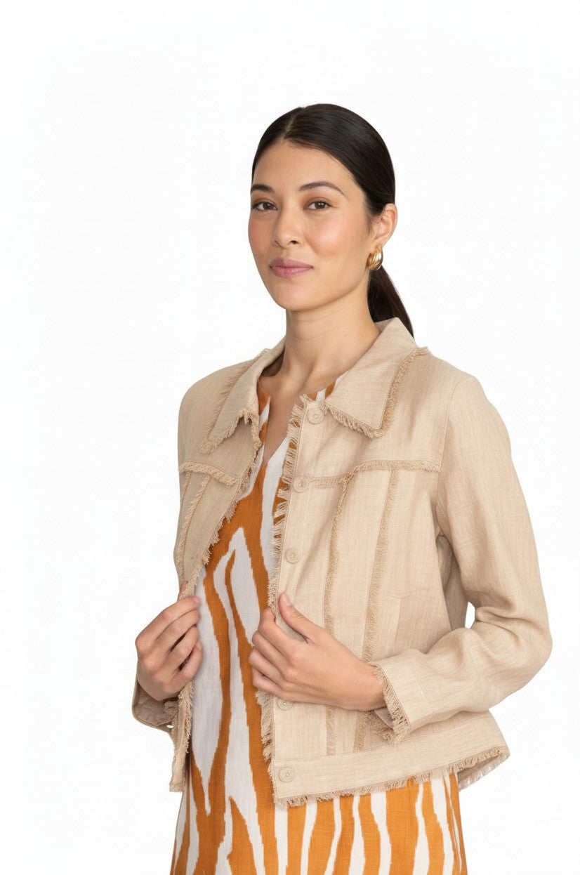 Model wearing The Strawberry Shop FOIL sand linen jacket with fringe trim over a patterned dress