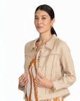 Model wearing The Strawberry Shop FOIL sand linen jacket with fringe trim over a patterned dress