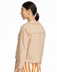 Model wearing a sand-colored FOIL linen fringe jacket with textured trim from The Strawberry Shop