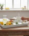The Strawberry Shop Limonata serving tray with a lemon and leaf pattern on a blue and white striped background. Features wooden handles.